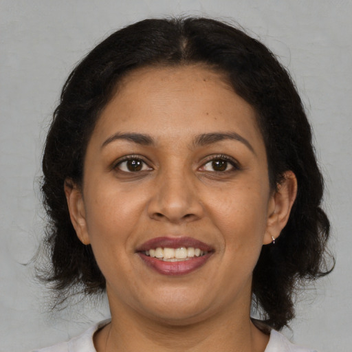 Joyful latino adult female with medium  brown hair and brown eyes
