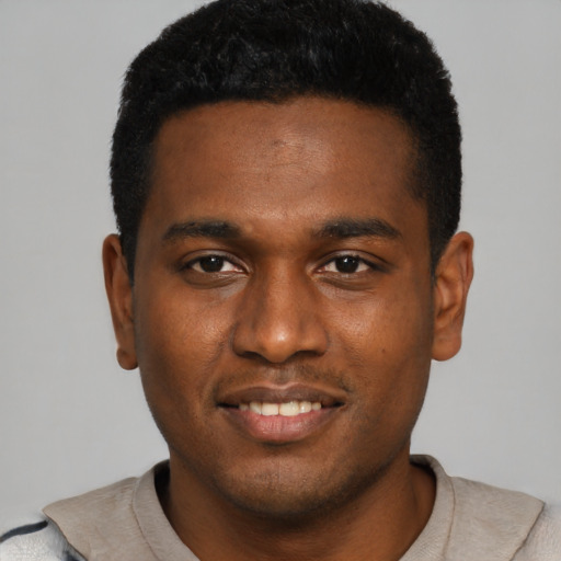 Joyful black young-adult male with short  black hair and brown eyes