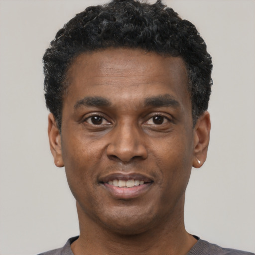 Joyful black young-adult male with short  black hair and brown eyes