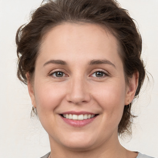 Joyful white young-adult female with medium  brown hair and grey eyes