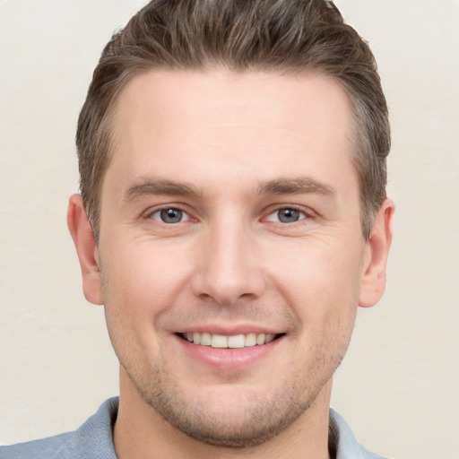 Joyful white young-adult male with short  brown hair and grey eyes