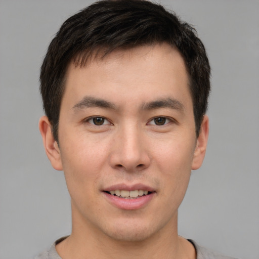 Joyful asian young-adult male with short  brown hair and brown eyes