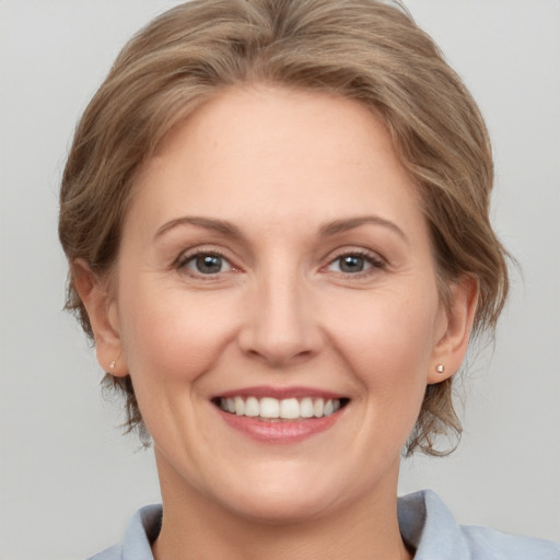 Joyful white adult female with medium  brown hair and grey eyes