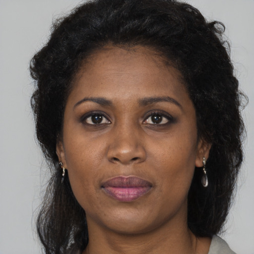 Joyful black young-adult female with long  brown hair and brown eyes