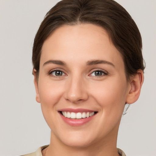 Joyful white young-adult female with medium  brown hair and grey eyes