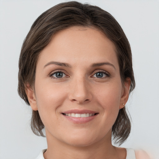 Joyful white young-adult female with medium  brown hair and grey eyes