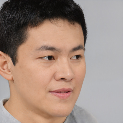 Joyful asian young-adult male with short  brown hair and brown eyes
