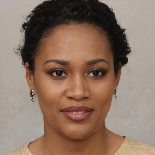 Joyful black young-adult female with short  black hair and brown eyes
