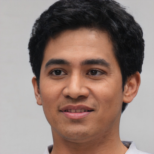 Joyful latino young-adult male with short  black hair and brown eyes