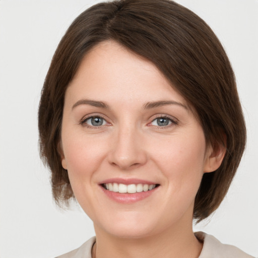 Joyful white young-adult female with medium  brown hair and grey eyes