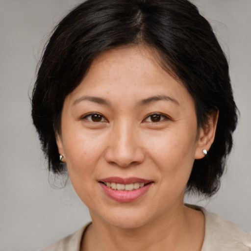 Joyful asian adult female with medium  brown hair and brown eyes