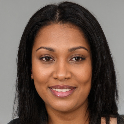 Joyful black young-adult female with long  brown hair and brown eyes