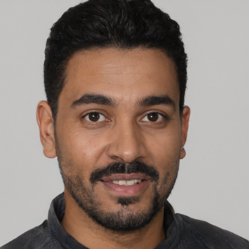 Joyful latino young-adult male with short  black hair and brown eyes