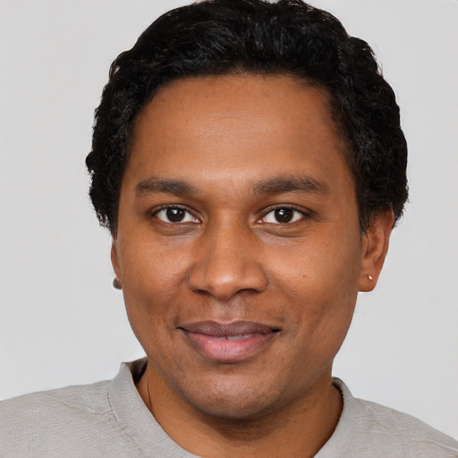 Joyful black adult male with short  black hair and brown eyes