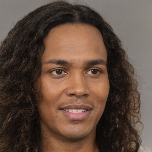 Joyful black young-adult male with long  brown hair and brown eyes