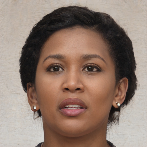 Joyful black young-adult female with short  black hair and brown eyes