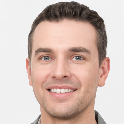 Joyful white young-adult male with short  brown hair and grey eyes