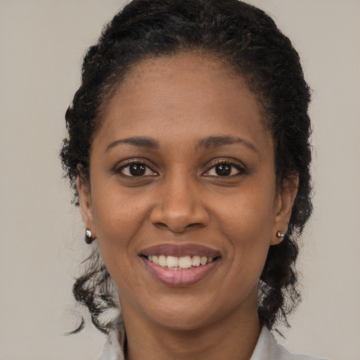 Joyful black young-adult female with long  black hair and brown eyes