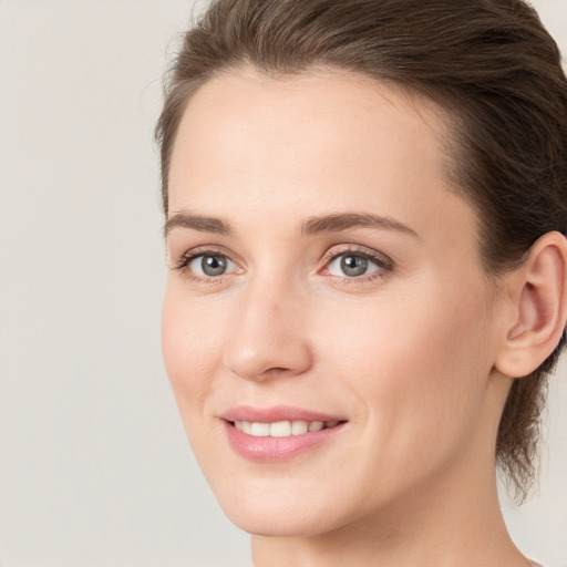 Joyful white young-adult female with medium  brown hair and grey eyes