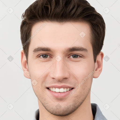 Joyful white young-adult male with short  brown hair and grey eyes