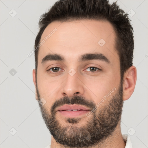 Joyful white young-adult male with short  black hair and brown eyes