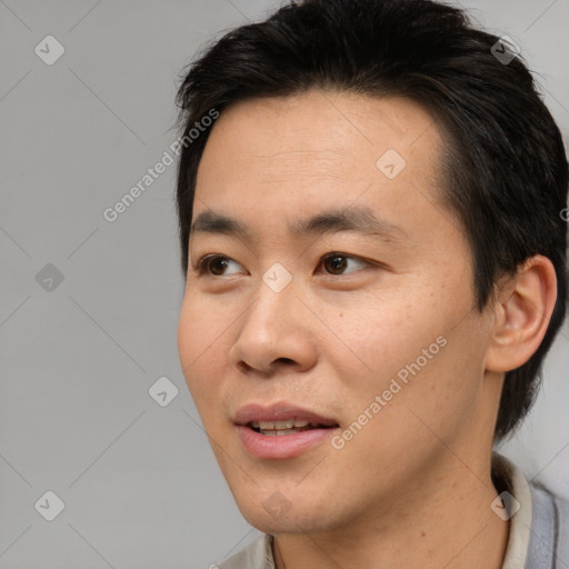 Joyful asian young-adult male with short  brown hair and brown eyes