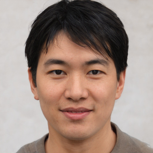 Joyful asian young-adult male with short  brown hair and brown eyes