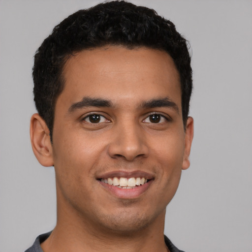 Joyful latino young-adult male with short  black hair and brown eyes