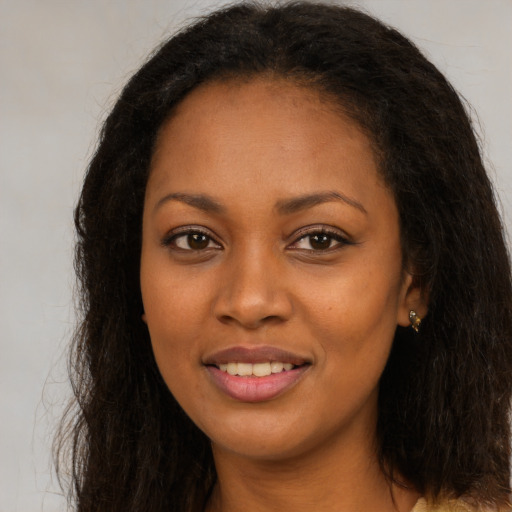 Joyful black young-adult female with long  brown hair and brown eyes