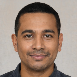 Joyful latino young-adult male with short  black hair and brown eyes
