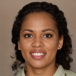 Joyful black young-adult female with long  brown hair and brown eyes