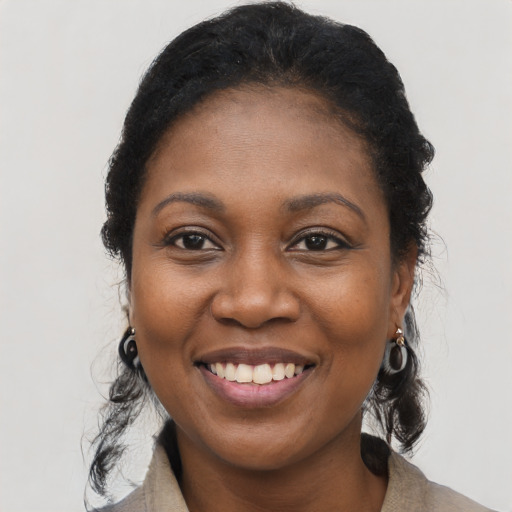 Joyful black young-adult female with long  black hair and brown eyes