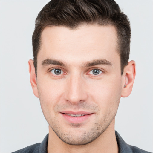 Joyful white young-adult male with short  brown hair and grey eyes