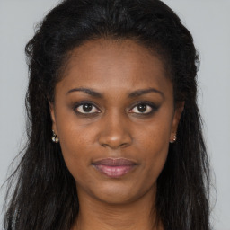 Joyful black young-adult female with long  brown hair and brown eyes