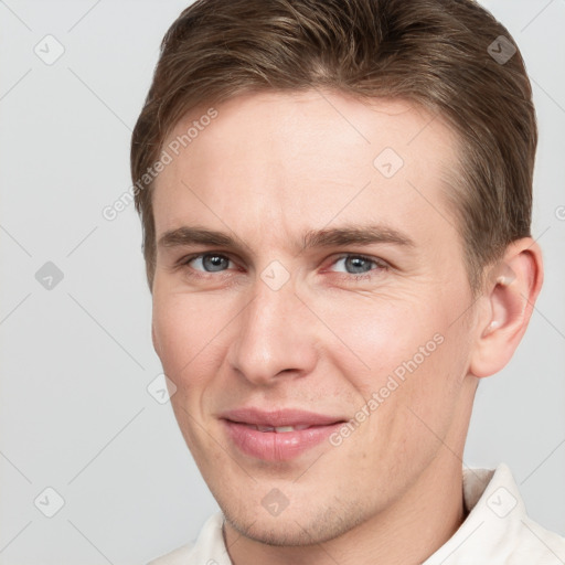 Joyful white young-adult male with short  brown hair and grey eyes