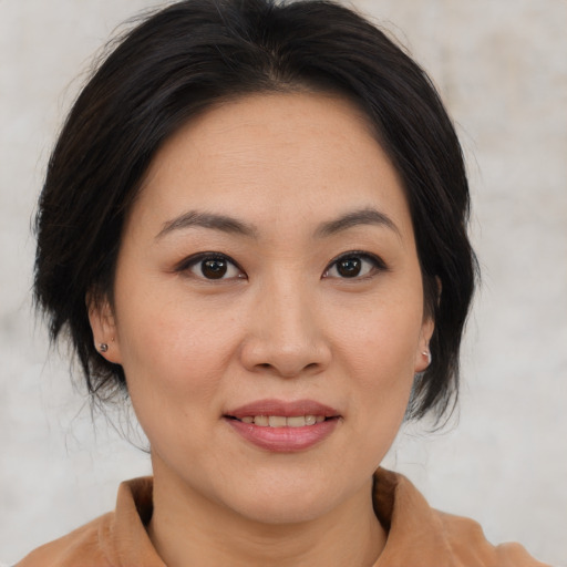 Joyful asian adult female with medium  brown hair and brown eyes