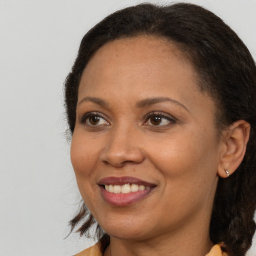 Joyful black adult female with long  brown hair and brown eyes
