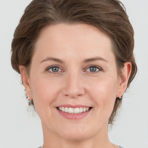 Joyful white young-adult female with medium  brown hair and grey eyes