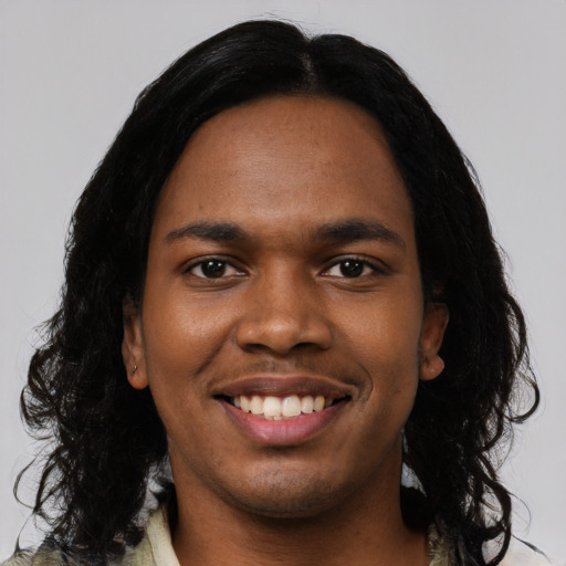 Joyful black young-adult male with long  black hair and brown eyes