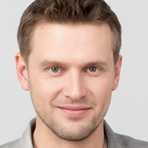 Joyful white young-adult male with short  brown hair and grey eyes