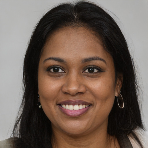 Joyful black young-adult female with long  brown hair and brown eyes