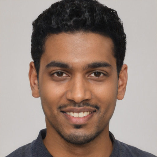 Joyful black young-adult male with short  black hair and brown eyes