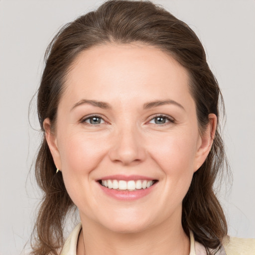 Joyful white young-adult female with medium  brown hair and grey eyes