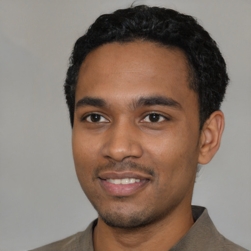 Joyful black young-adult male with short  black hair and brown eyes