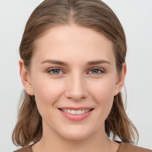 Joyful white young-adult female with medium  brown hair and grey eyes