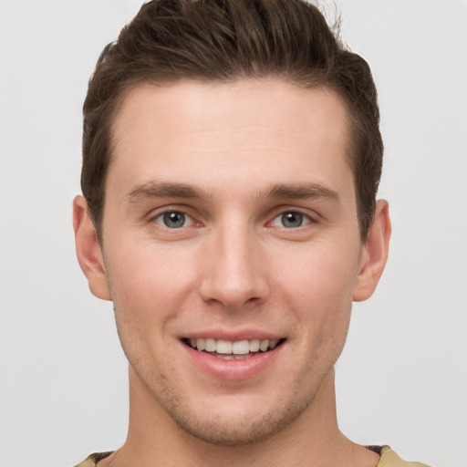 Joyful white young-adult male with short  brown hair and grey eyes