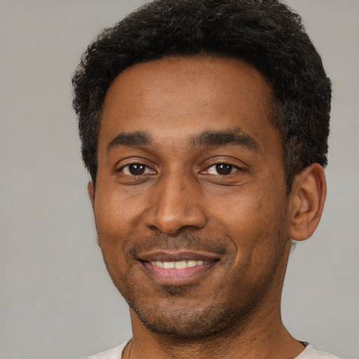 Joyful black young-adult male with short  black hair and brown eyes