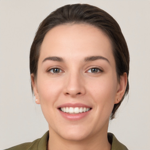 Joyful white young-adult female with medium  brown hair and grey eyes