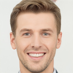 Joyful white young-adult male with short  brown hair and grey eyes