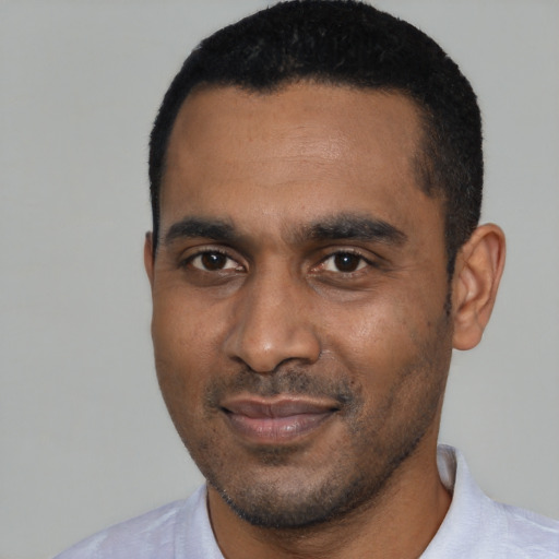 Joyful black young-adult male with short  black hair and brown eyes